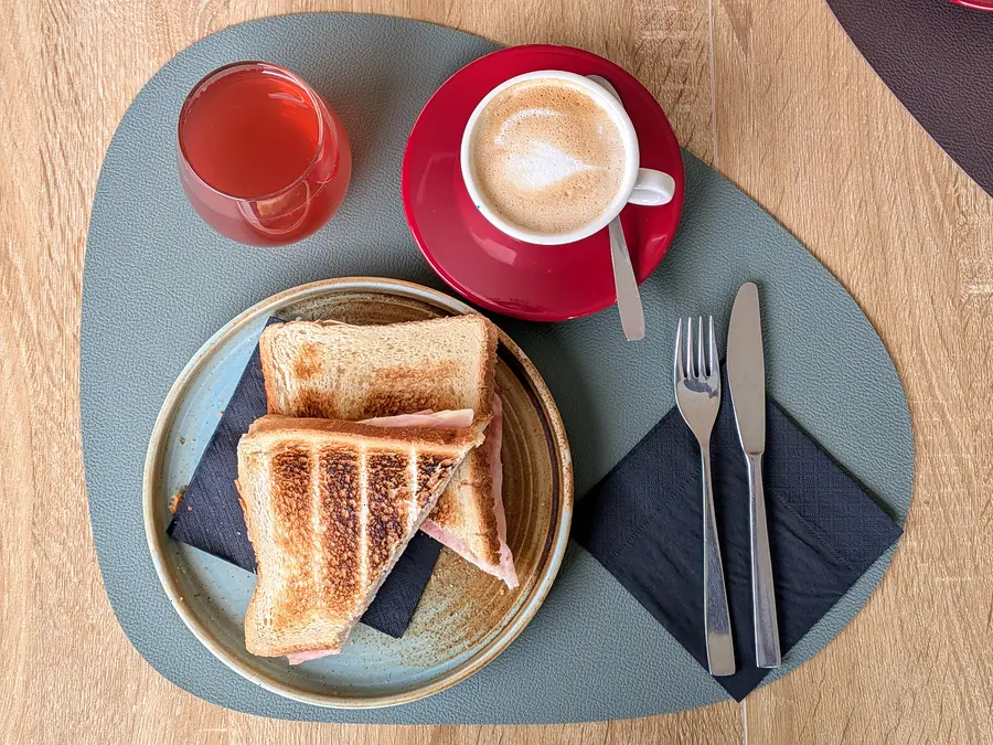 Brioche con confettura, cappuccino e succo per la colazione